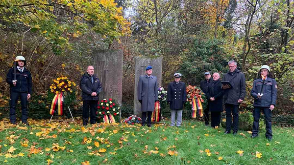 Menschen auf dem Friedhof mit Kränzen