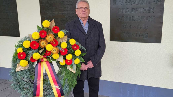 Ein Mann neben einem großen Kranz.