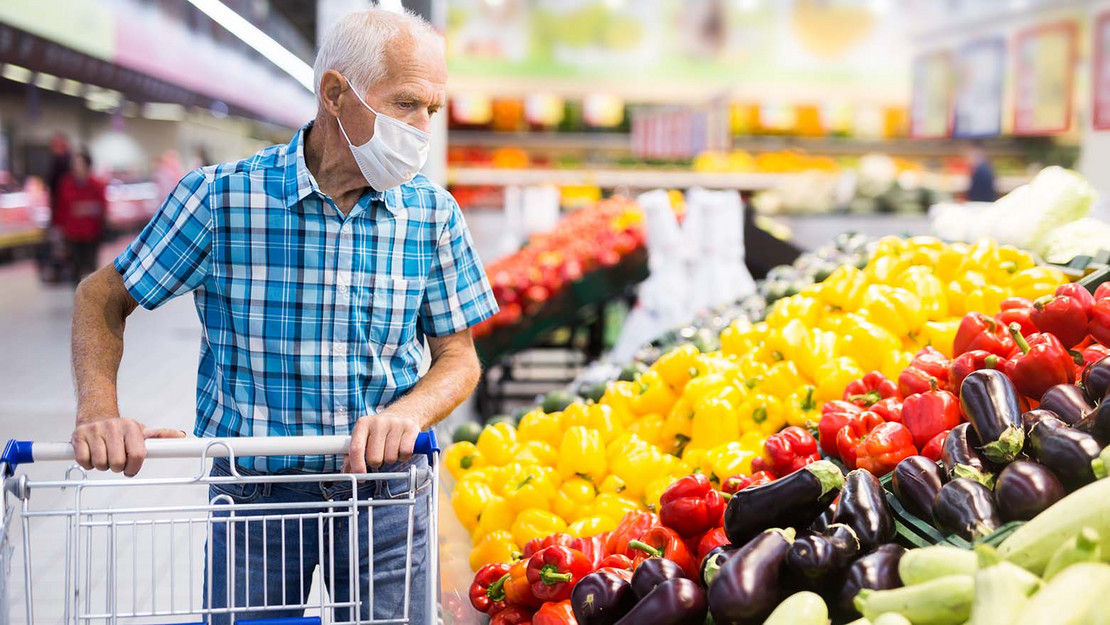 Älterer Mann mit Maske beim Einkauf am Gemüseregal