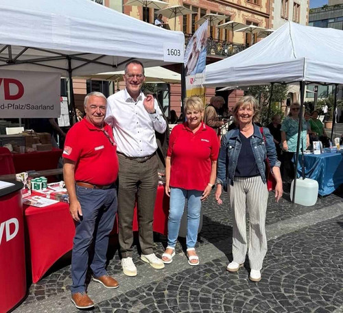 Vier Personen posieren für ein Gruppenfoto vor dem Stand. 