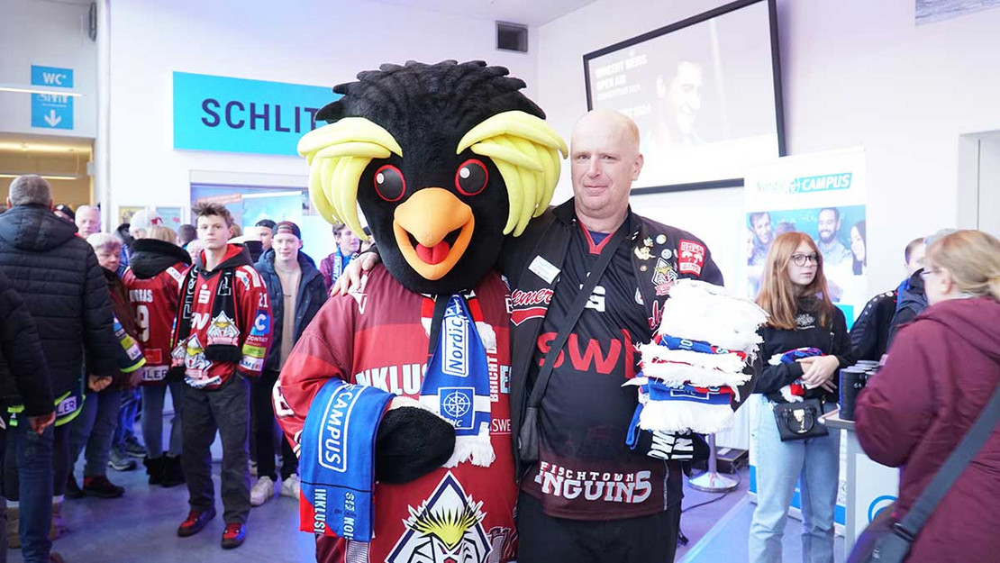 Maskottchen in Pinguin-Verkleidung und ein ein Mensch. 