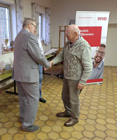 Ein Mann gratuliert einem anderen und schüttelt seine Hand. 