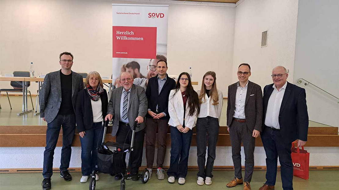 Gruppenbild mit 8 Personen vor einem SoVD-Aufsteller. 