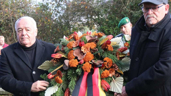 Zwei Männer tragen einen großen Kranz.