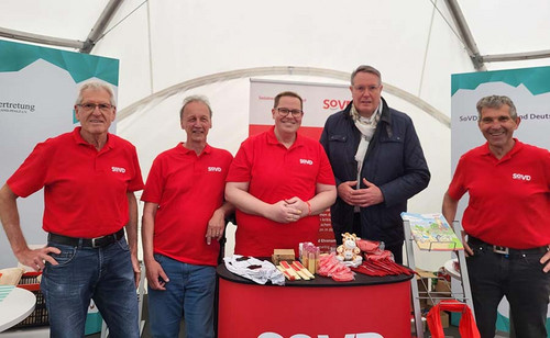 Fünf Personen, darunter Rheinland-Pfalz' Ministerpräsident Alexander Schweitzer, am SoVD-Infostand. 
