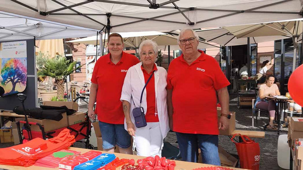 V Thorsten Greiner sowie Martina und Joachim Serowi am SoVD-Infostand.