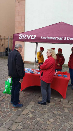 Gespräch SoVD-Mitglied mit Passanten am Infostand.