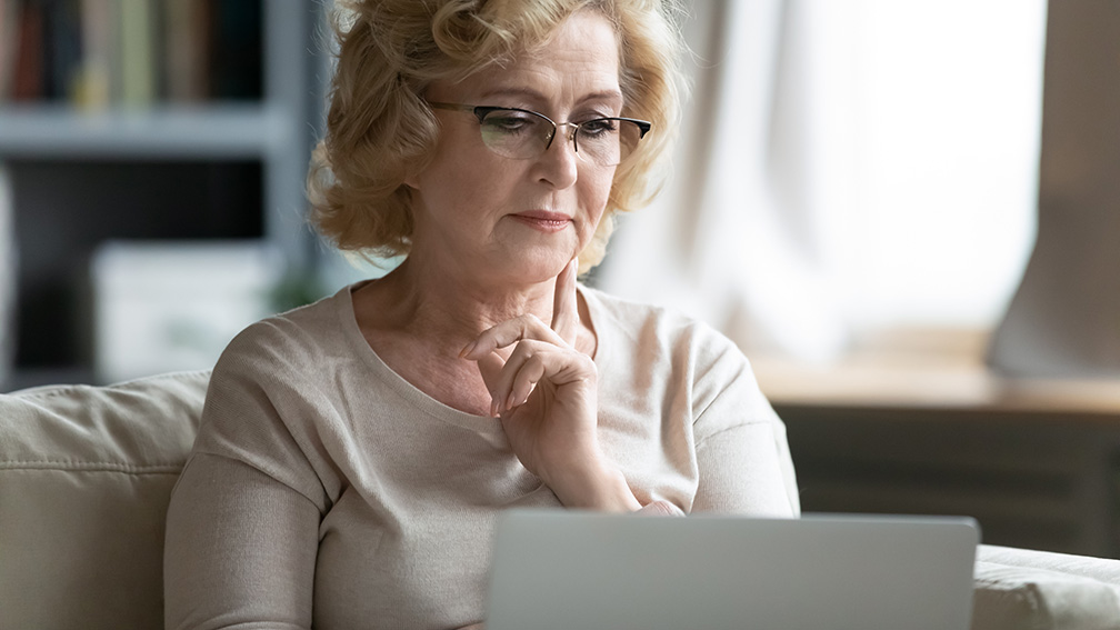 Frau blickt nachdenklich auf einen Laptop