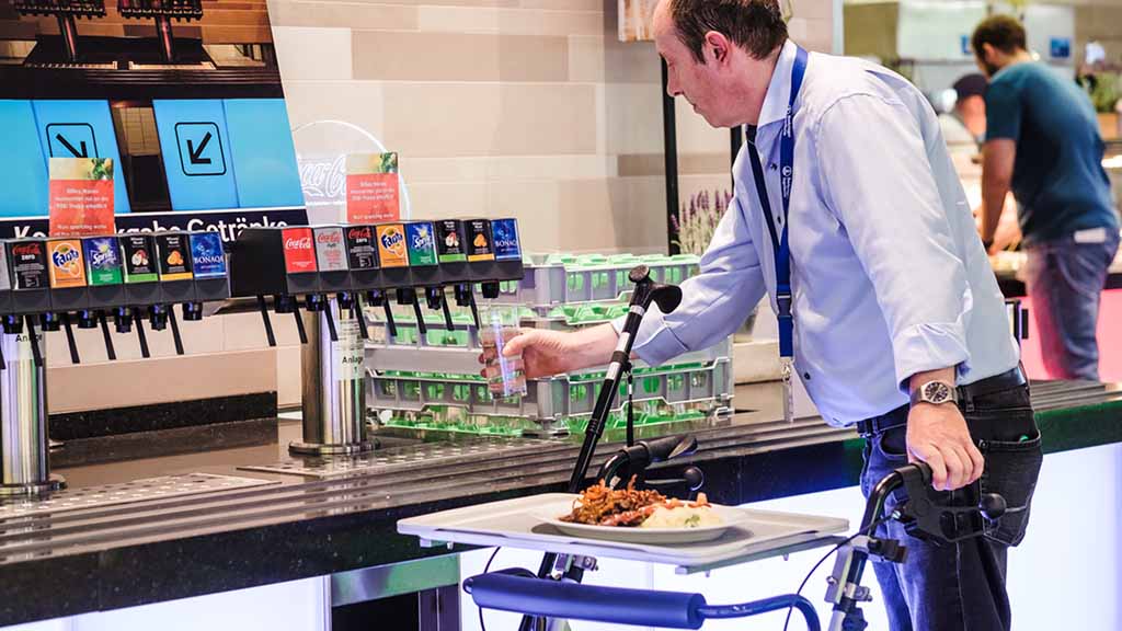 Mann mit Rollator in einer Kantine