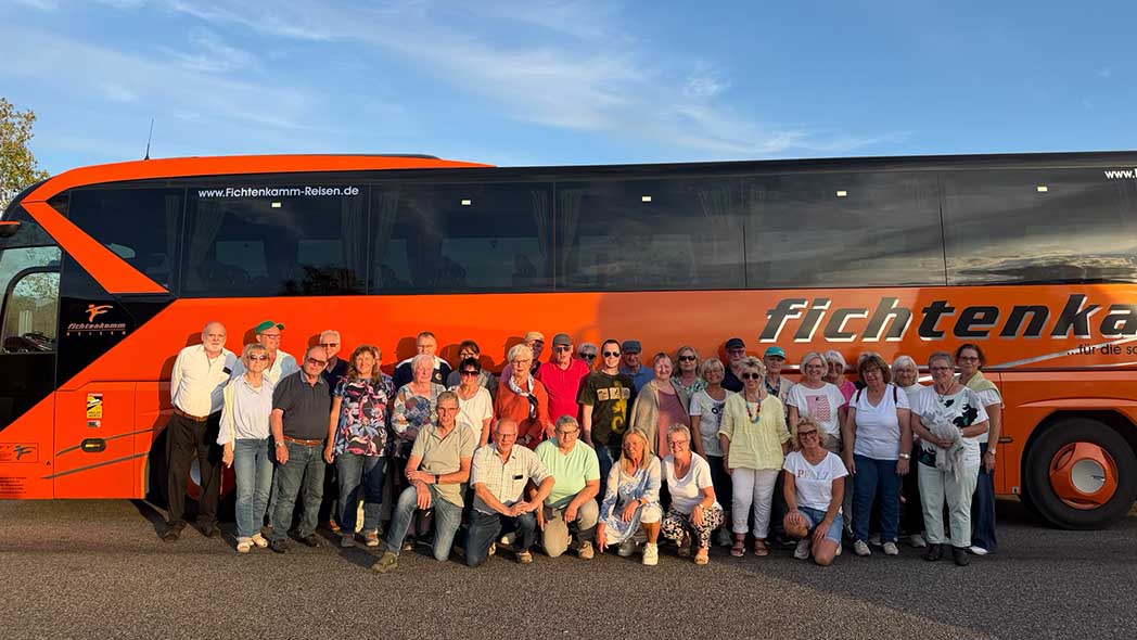 Große Gruppe Menschen vor einem Reisebus.
