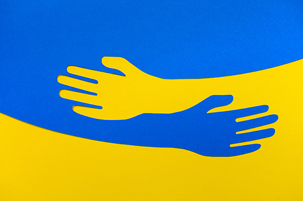 Zwei gemalte Hände strecken sich zueinander aus in den Farben der Ukraine